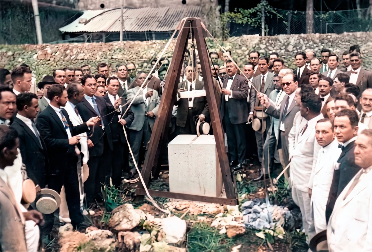Formal funeral service with large gathering of men in dark suits standing around wooden casket and grave