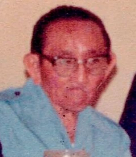Portrait of a man wearing glasses and a blue shirt against a beige background