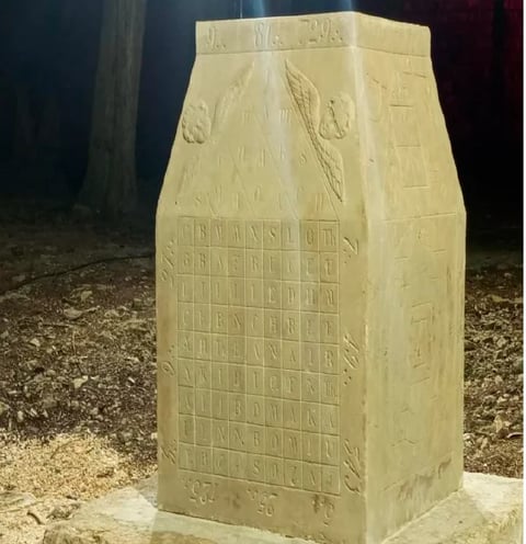 Carved sandstone sculpture of a grain sack with wheat stalks and decorative relief lettering
